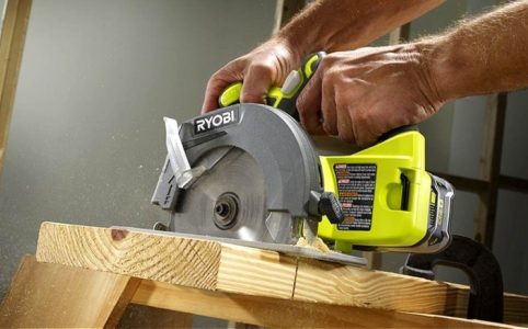 A beginner woodworker using the Ryobi 18V circular saw to cut plywood for a shelf project in a bright garage workshop