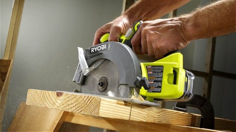A beginner woodworker using the Ryobi 18V circular saw to cut plywood for a shelf project in a bright garage workshop