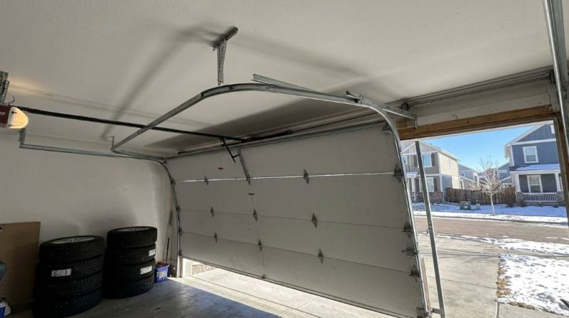 Technician inspecting low overhead garage door track alignment